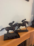 A pair of bronze sculptures of jockeys atop horses