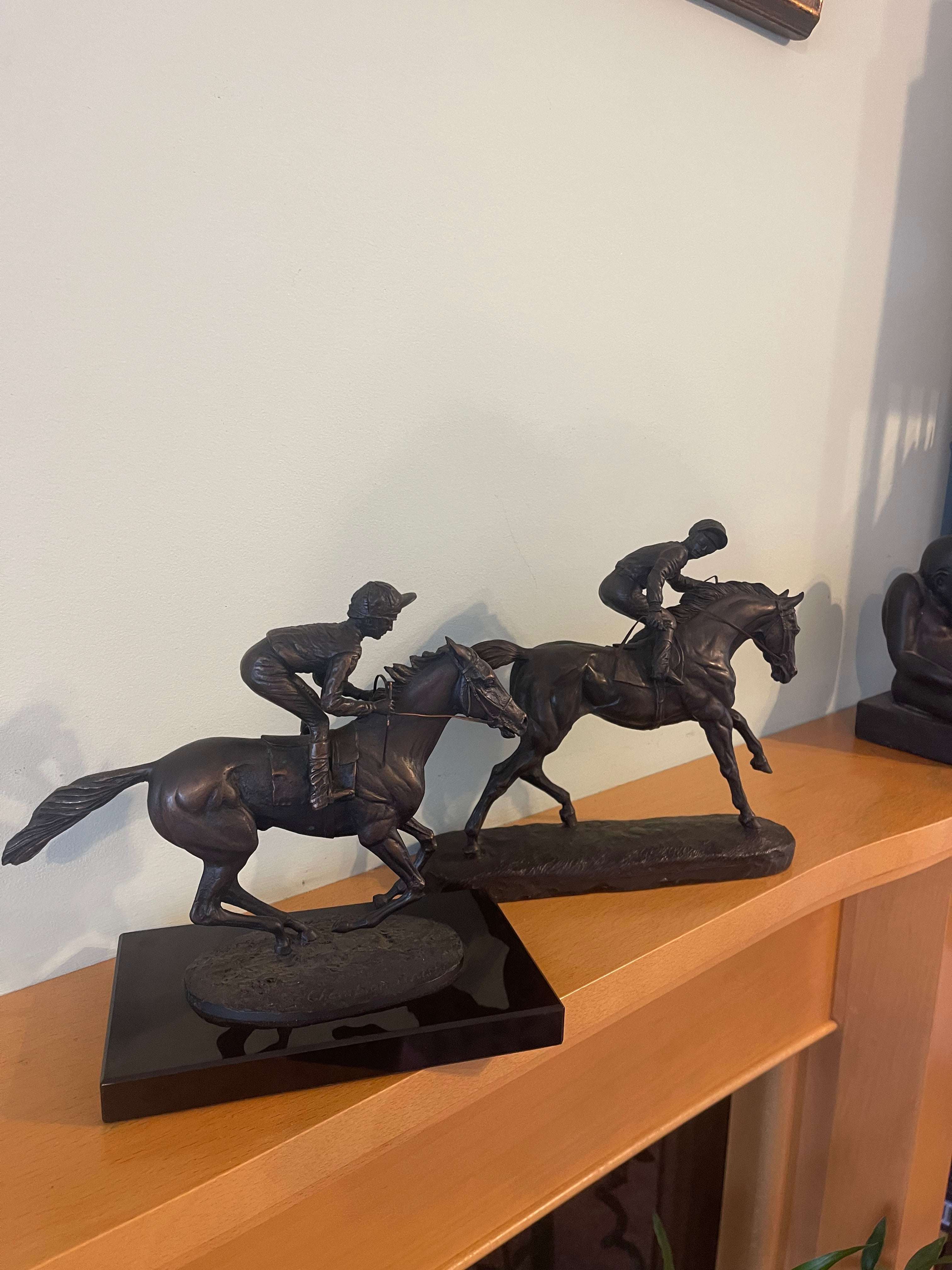 A pair of bronze sculptures of jockeys atop horses